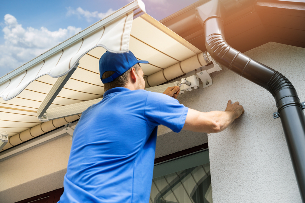 Man,Installing,Awning,On,House,Facade,Wall,Over,The,Balcony